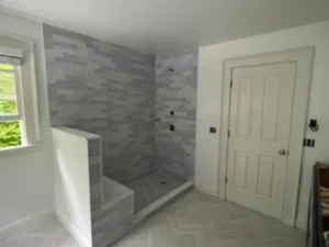 Bathroom painting in progress with tiled shower area and white walls, showcasing a modern, clean design.
