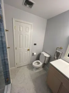 Minimalist bathroom layout featuring a white toilet and soft gray walls as part of a full bathroom upgrade.