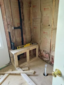Framing and rough plumbing phase of a Full Bathroom Remodel showing preparation for the vanity area.