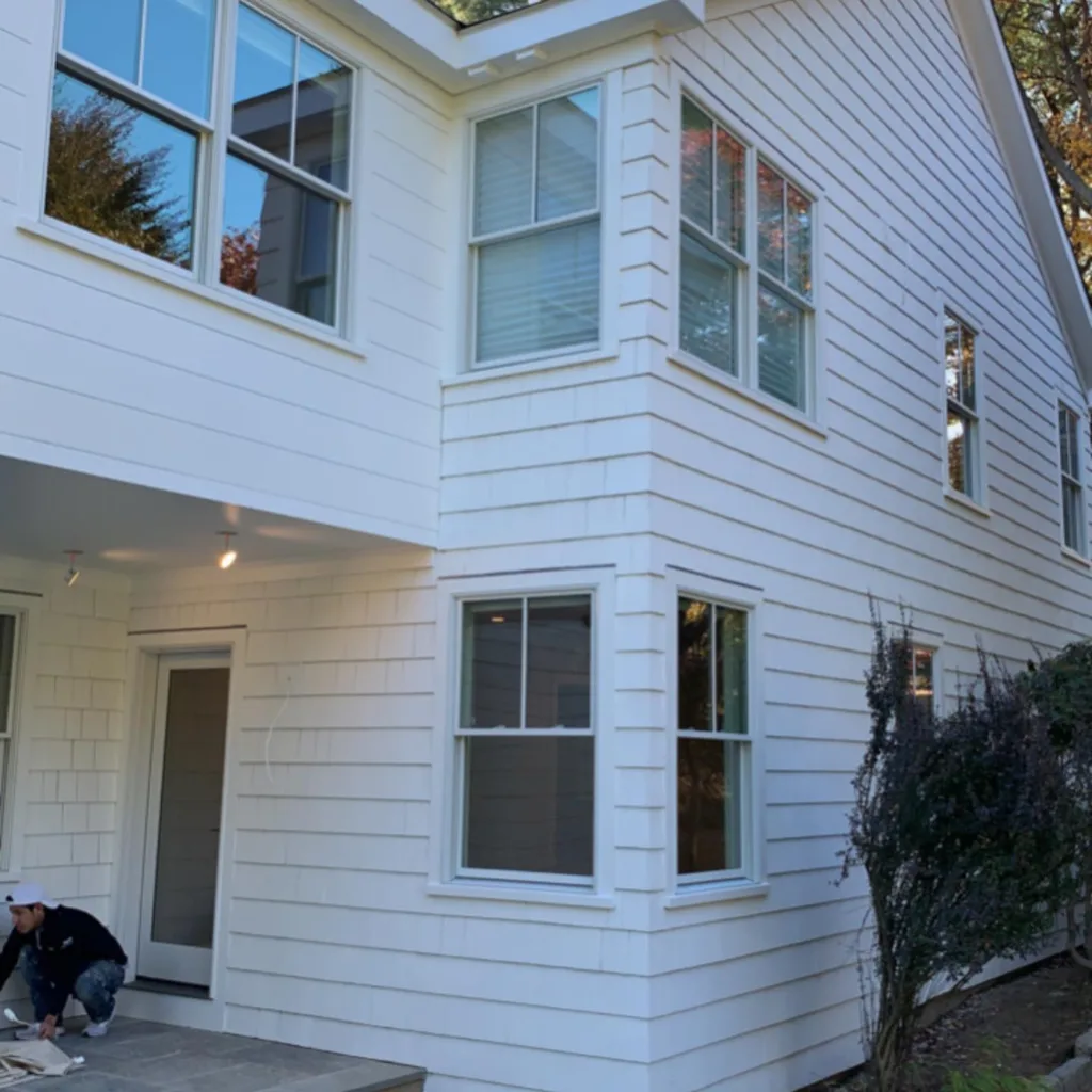 Painter working on the lower siding during the exterior house painting project