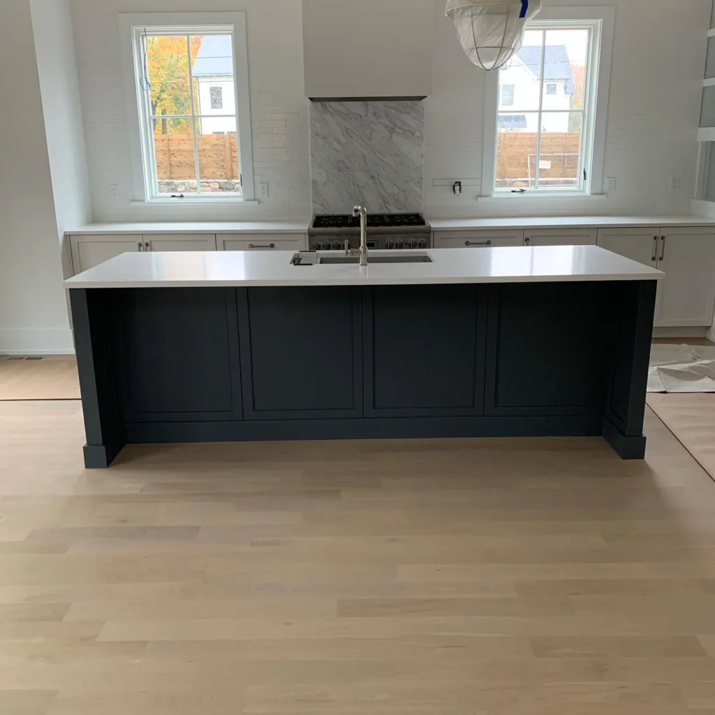 Completed kitchen island painting project featuring a dark painted base, a newly installed white countertop, and an undermount sink.