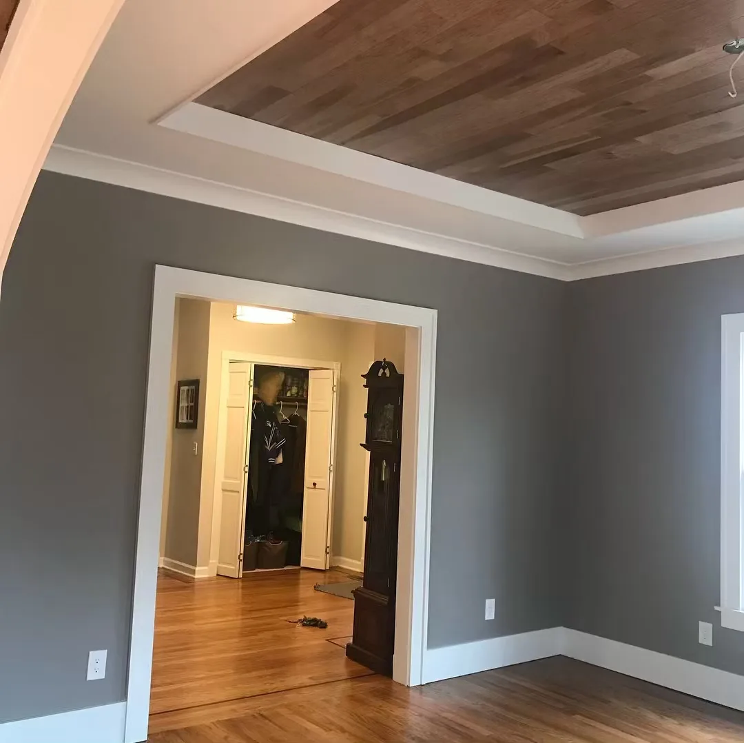 High-End Interior Renovation: Newly finished room showing the elegant wood floor, clean grey walls, and a new wood ceiling with crown molding.