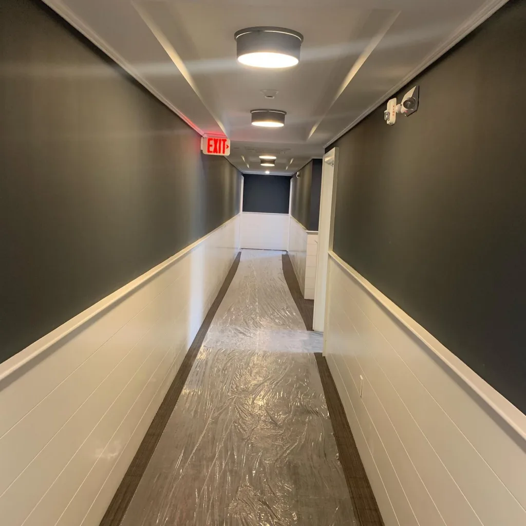 After Westport interior wall coating was completed, a newly painted commercial corridor features a protective plastic walkway.