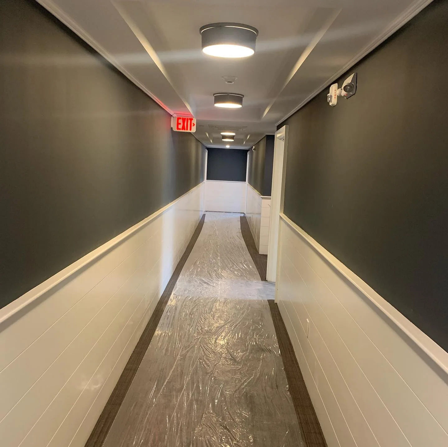 After Westport interior wall coating was completed, a newly painted commercial corridor features a protective plastic walkway.
